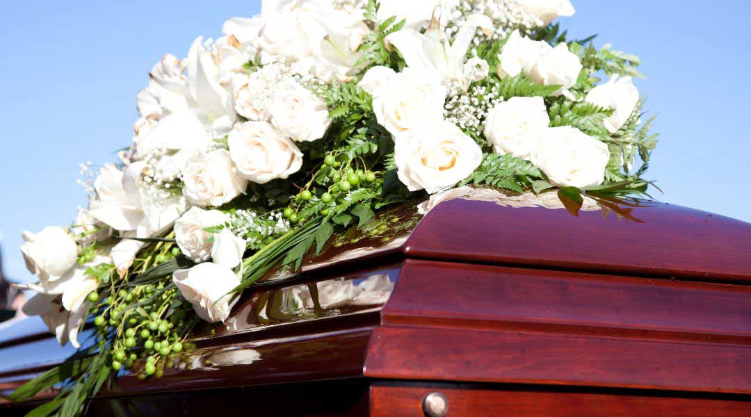 a coffin with white roses on top